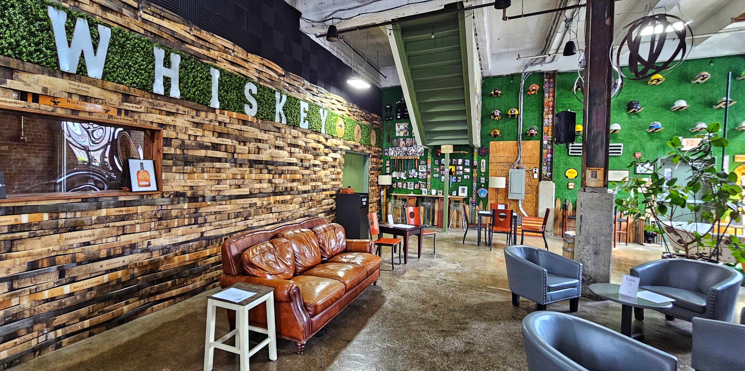 A tasting room featuring couches and the word "whiskey" on one wall, with firemen's hats and other decor on another wall.