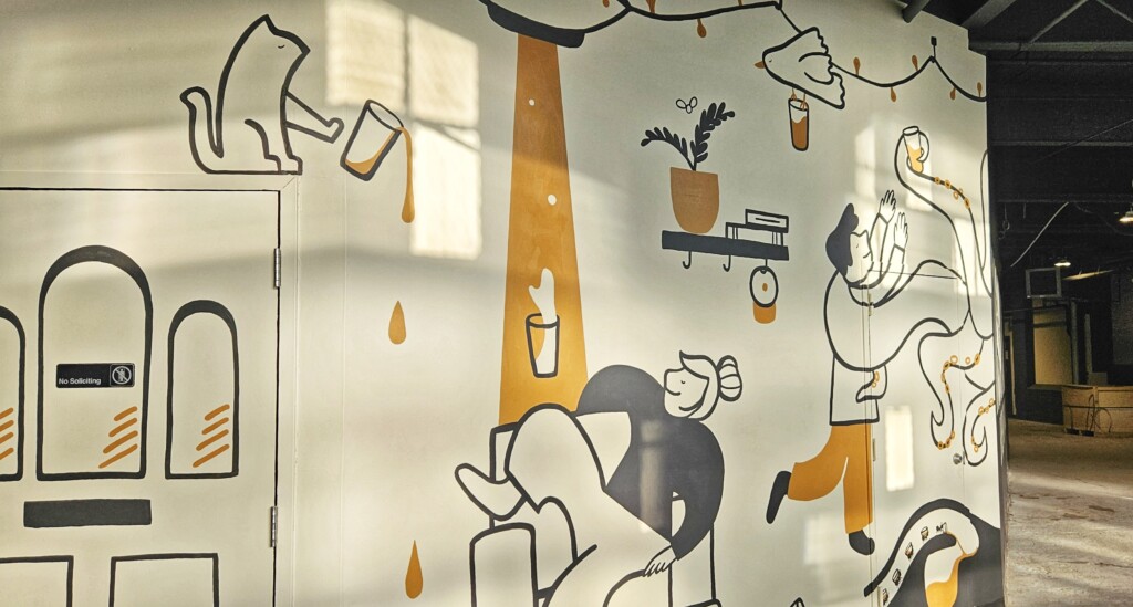 A colorful mural shows an alien spaceship beaming up a pint glass in a playful scene.